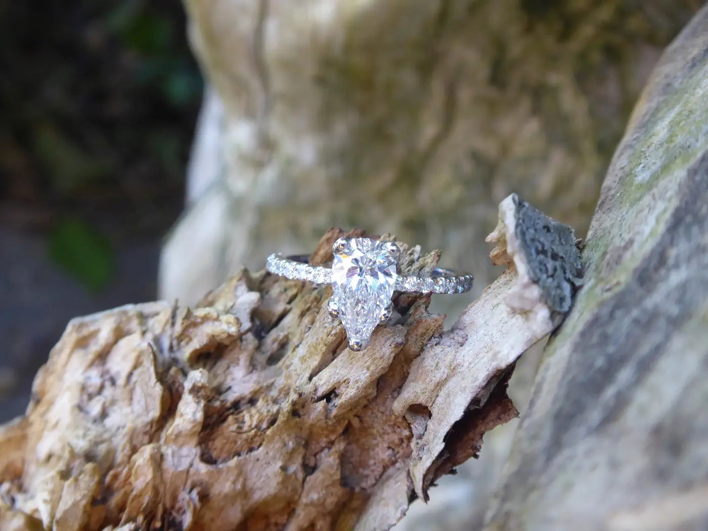 Bespoke white gold diamond engagement and wedding ring set resting on tree bark — handmade by Nude Jewellery London