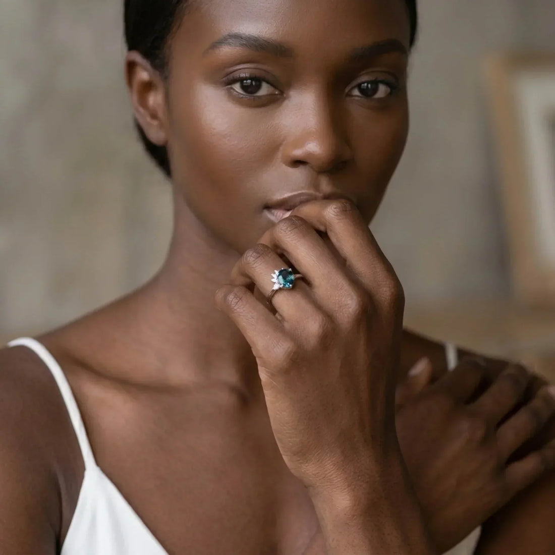 Selene teal sapphire and diamond asymmetric engagement ring in 18ct white gold, worn on model's hand — handmade by Nude Jewellery London