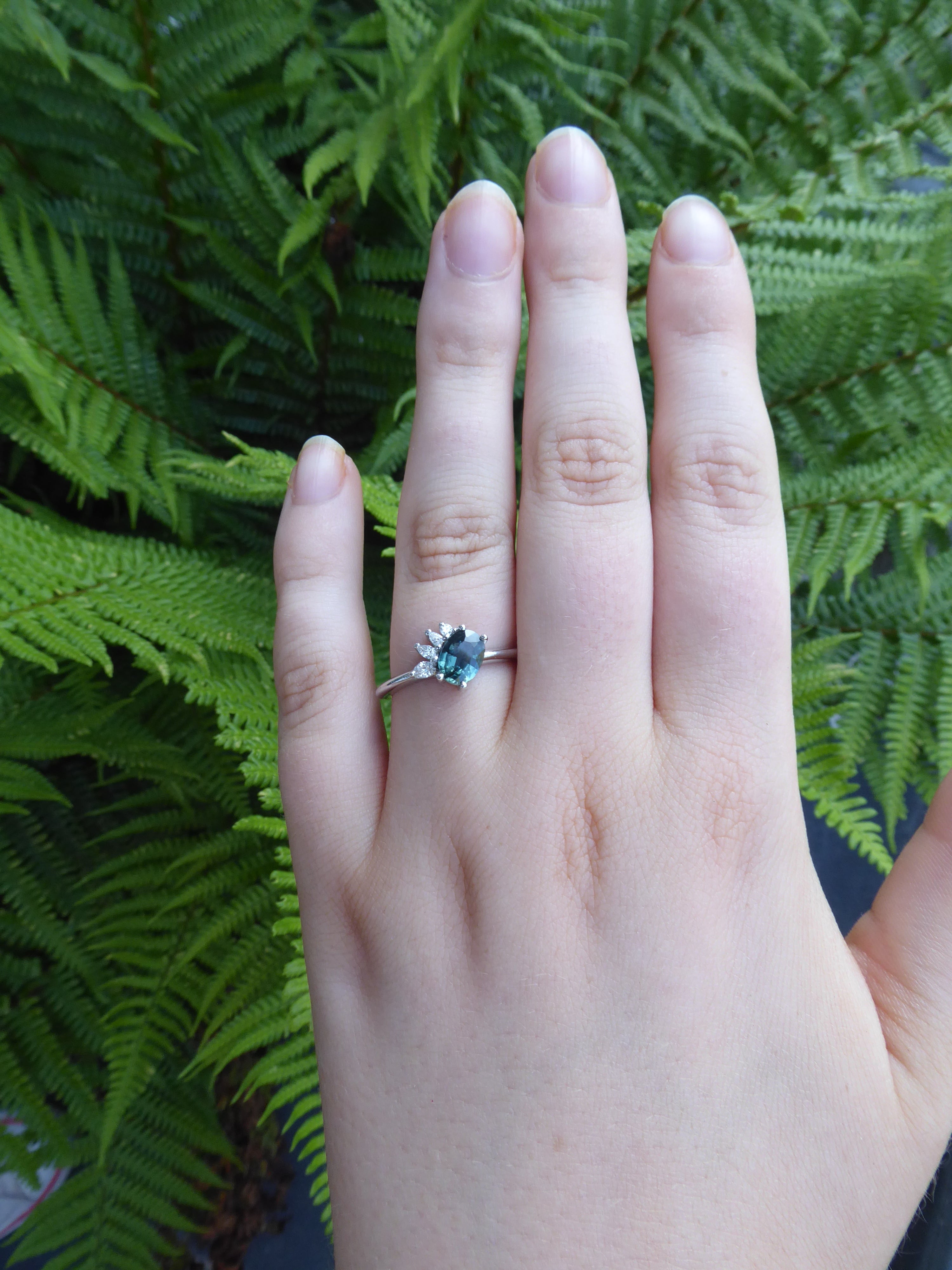 The Selene engagement ring - teal sapphire and diamonds, platinum with fern backgrounds.