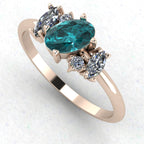 An angled perspective of the Atlantis teal sapphire ring, showcasing the handmade, contemporary design and the rich colour palette of the gemstones against the rose gold band.