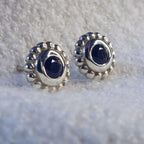Pair of sterling silver stud earrings featuring faceted black spinel gemstones with a millgrain beaded border.