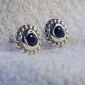 Pair of sterling silver stud earrings featuring faceted black spinel gemstones with a millgrain beaded border. 