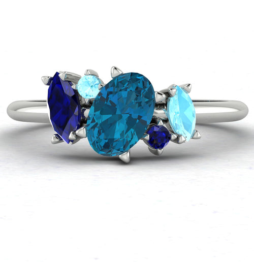 Front view of the Atlantis engagement ring featuring an asymmetrical arrangement of blue topaz and aquamarine gemstones in a polished white metal setting.