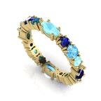 18ct yellow gold eternity ring featuring a gradient of blue gemstones including marquise-cut sapphires, aquamarines, and round blue topaz.