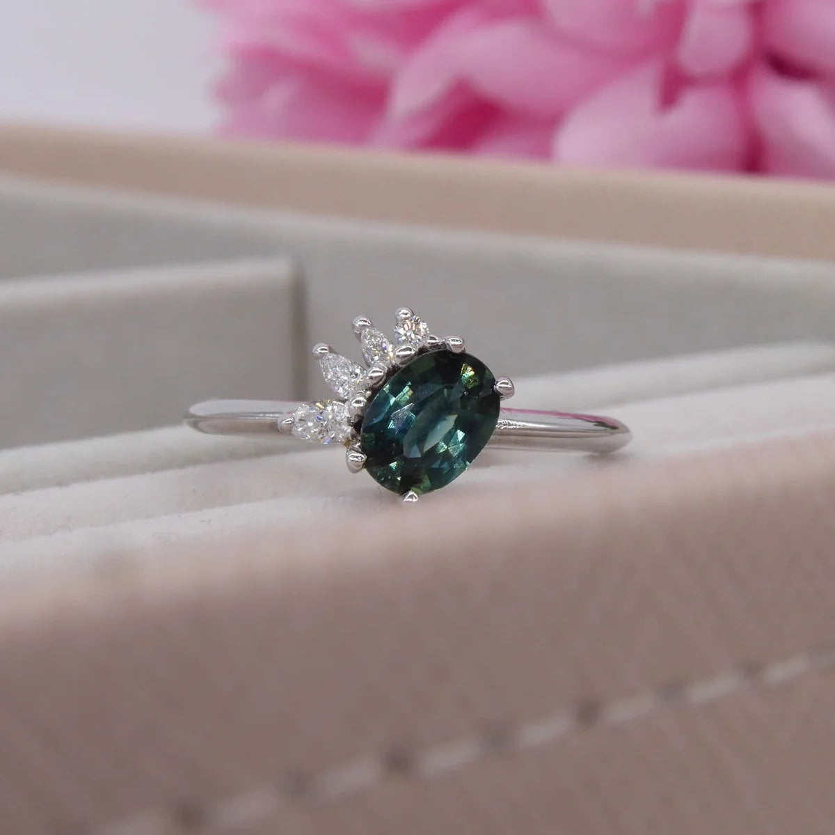 Selene oval teal sapphire and diamond asymmetric cluster engagement ring in 18ct white gold, presented in ring box showing the deep teal sapphire and diamond cluster, handmade in our London studio