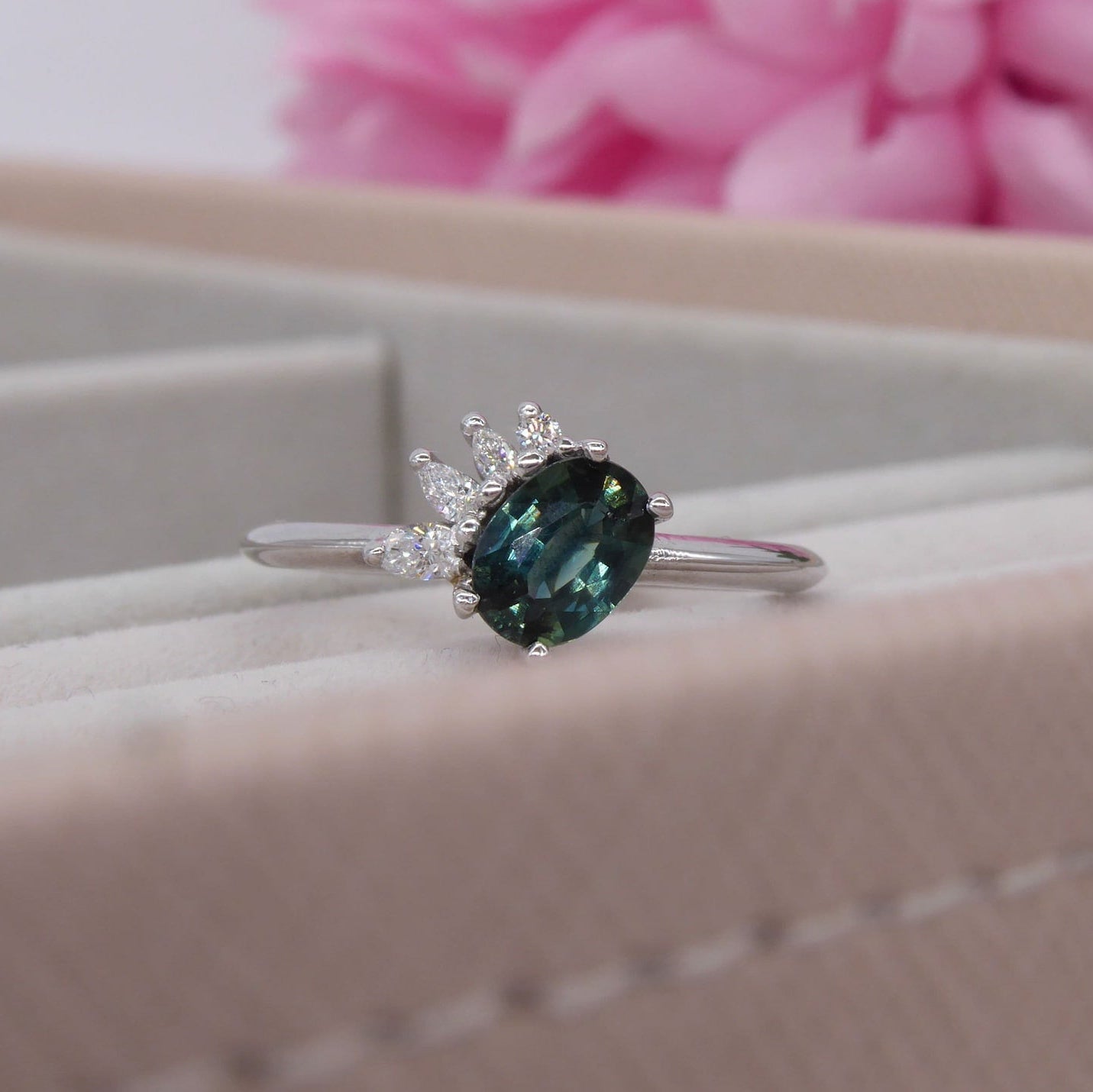 Selene oval teal sapphire and diamond engagement ring in white gold styled in ring box showing deep blue-green sapphire and diamond cluster