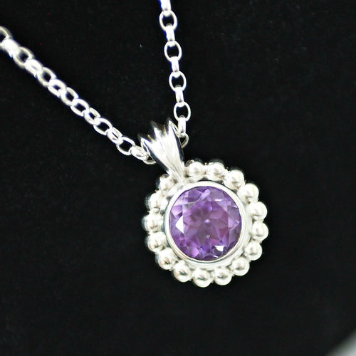 Silver necklace with a purple amethyst gemstone pendant on a black background