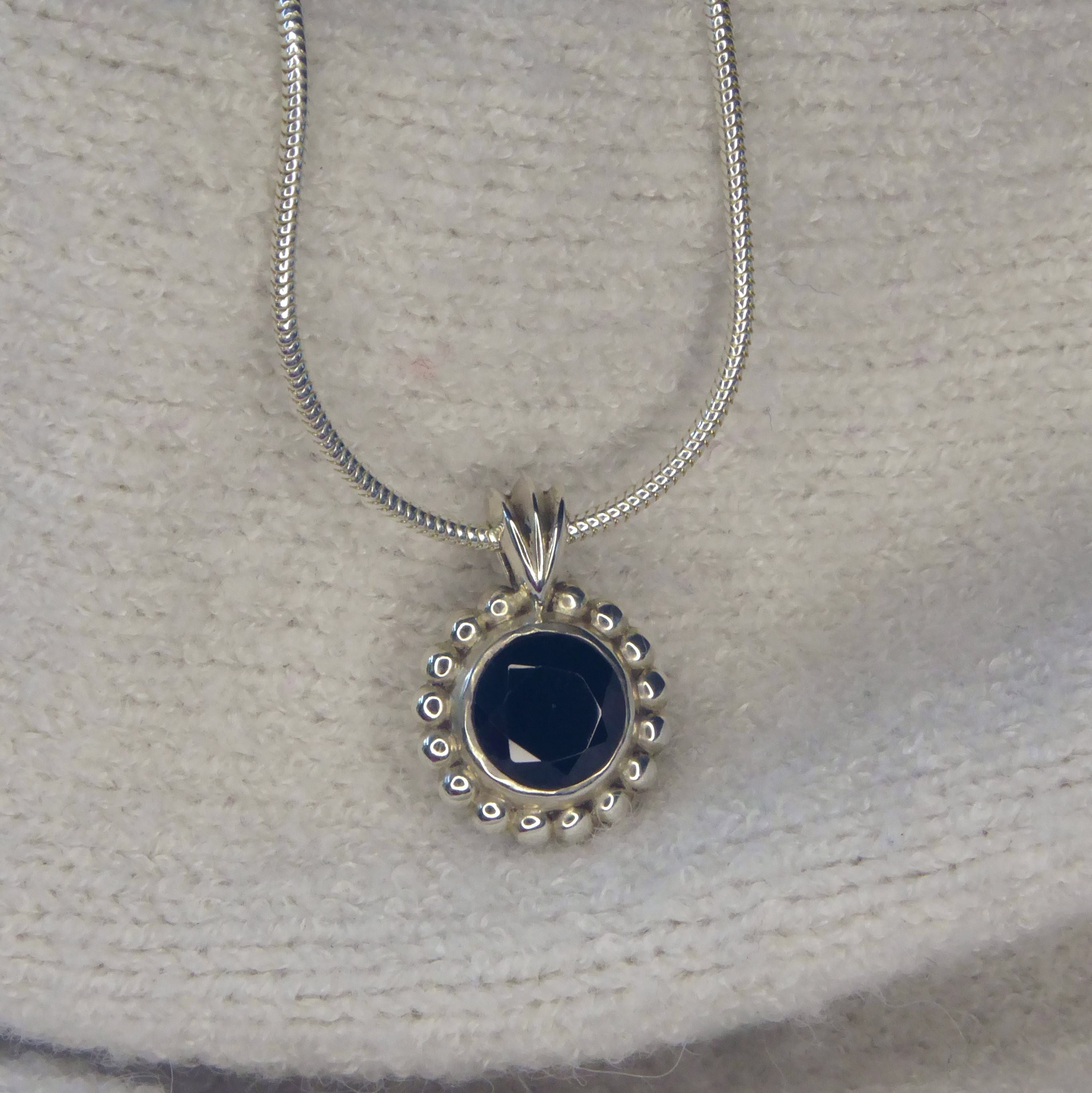 A front-facing view of the Alto Majestic pendant, featuring a round, brilliant-cut black spinel gemstone set within a high-polished recycled silver geometric frame.