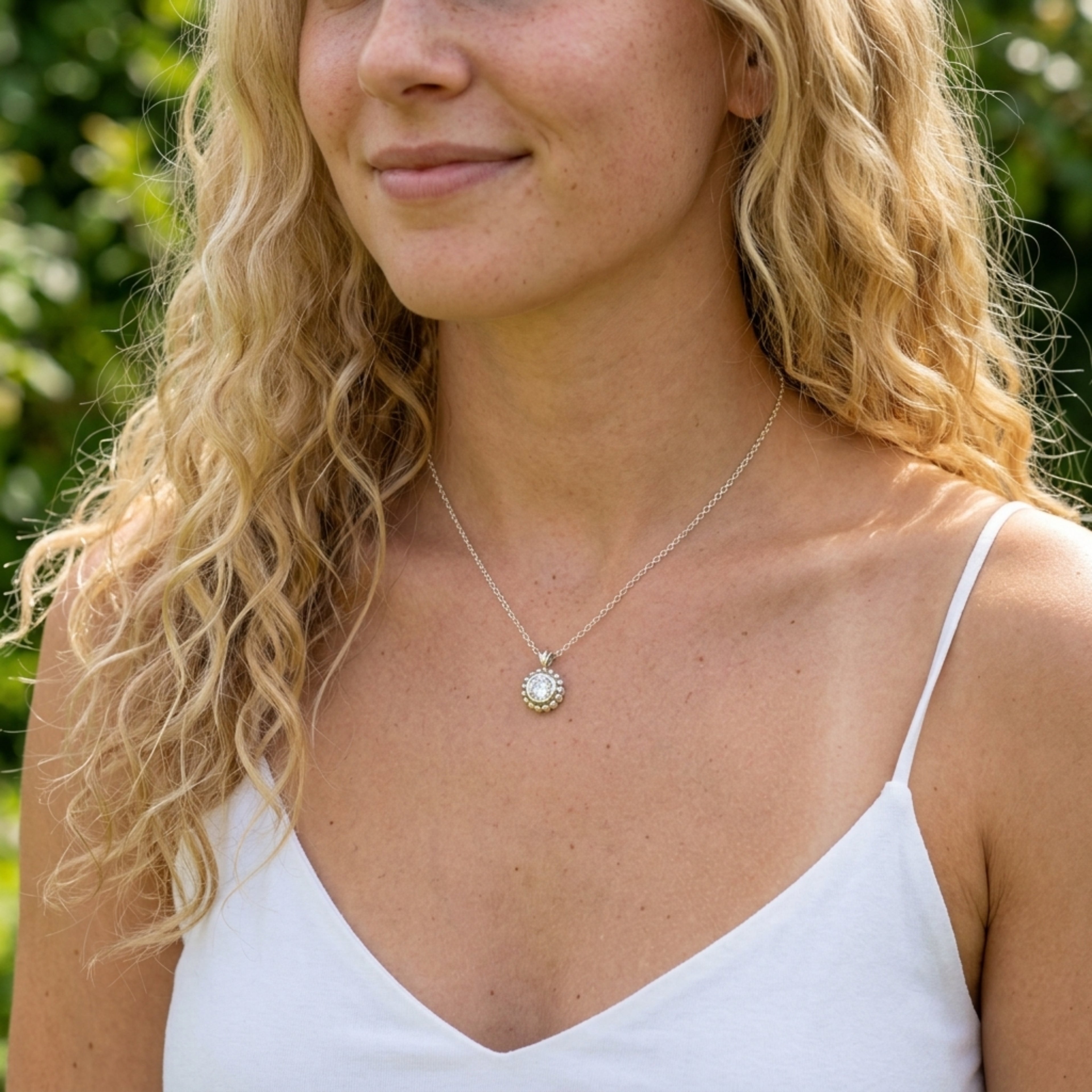 Model wearing the Alto Majestic pendant, featuring a clear, sparkling round white topaz gemstone set within a high-polished recycled silver geometric frame.