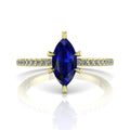 Profile view of the Amoret engagement ring in 18ct yellow gold showing the elegant silhouette of the marquise blue sapphire and diamond-set shoulders.
