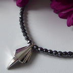 Close-up detail of the faceted hematite beads and the architectural silver pendant setting.