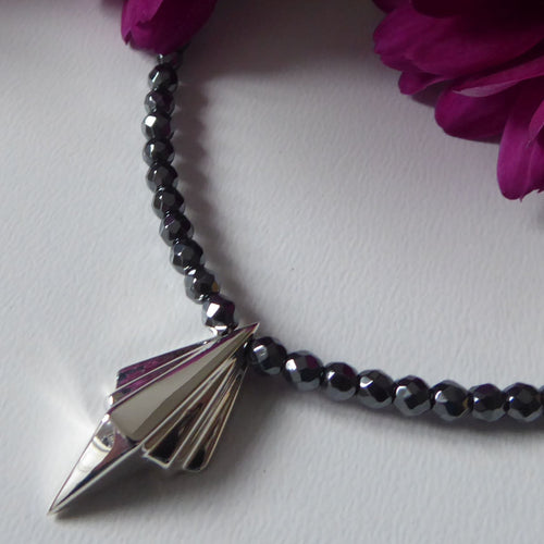 Close-up detail of the faceted hematite beads and the architectural silver pendant setting.