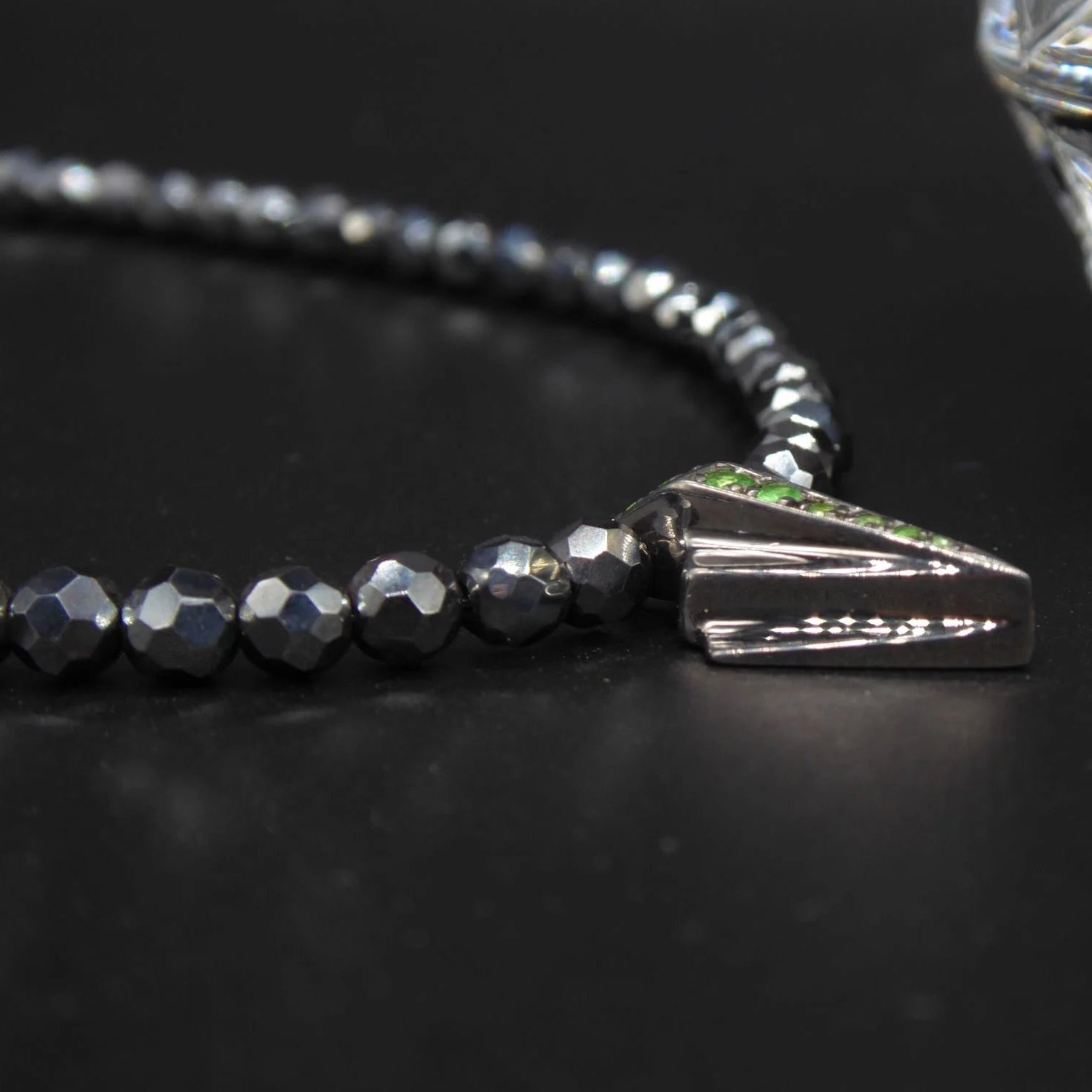 Close-up side view  of the green tsavorite garnet and the geometric silver Art Deco setting.