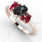 An angled perspective of the Atlantis ring, highlighting the bold contrast between the dark black diamond, the crimson rubies, and the warm, polished 18ct rose gold band.