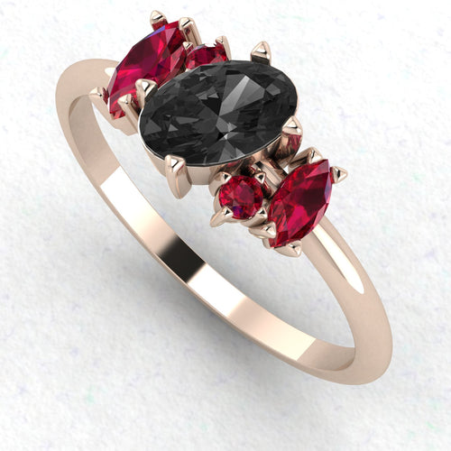 An angled perspective of the Atlantis ring, highlighting the bold contrast between the dark black diamond, the crimson rubies, and the warm, polished 18ct rose gold band.