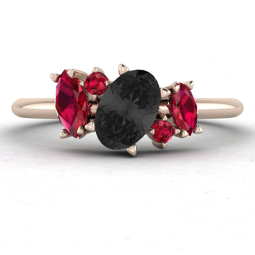 Front view of the Atlantis engagement ring, featuring a central pear-shaped black diamond framed by an asymmetrical cluster of deep red rubies and white diamonds in 18ct rose gold.