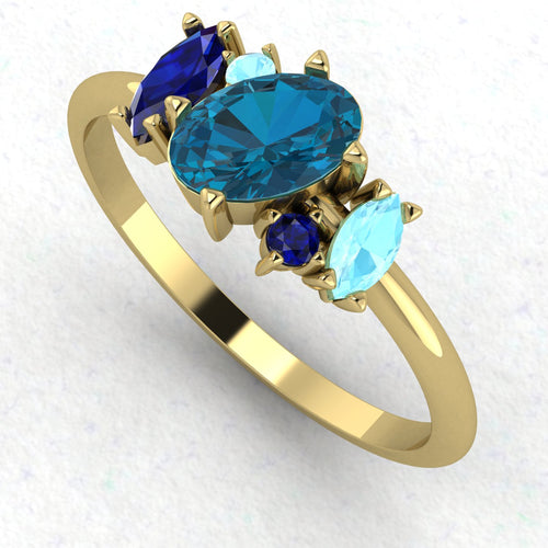An angled perspective of the Atlantis ring highlighting the contemporary, organic design and the rich tones of the blue stones against the yellow gold.