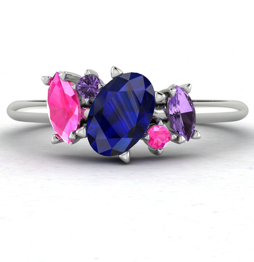 Front view of the Atlantis engagement ring, featuring an asymmetrical cluster of sapphires in shades of blue and teal set in white metal.