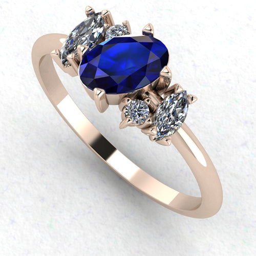 An angled perspective of the Atlantis sapphire ring, showcasing the organic, handmade texture of the rose gold and the brilliant contrast of the blue gemstones.