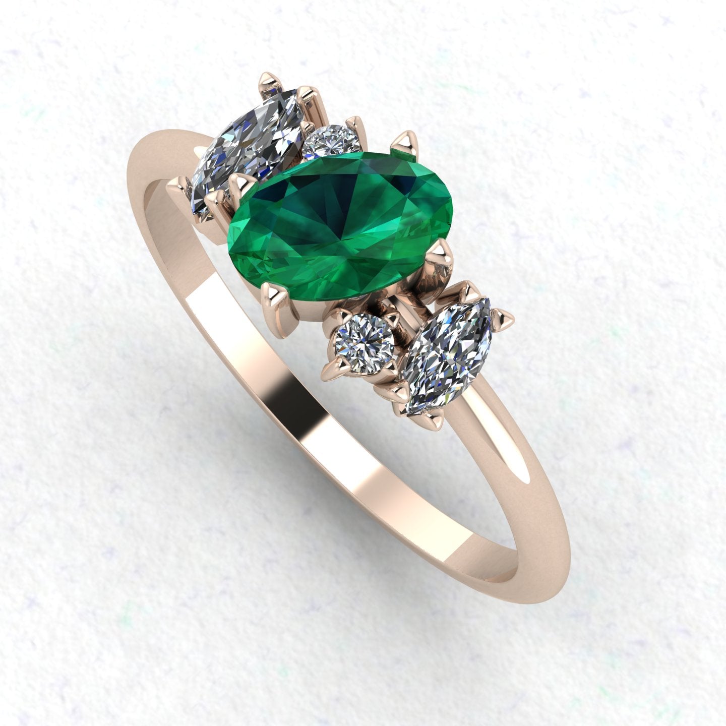 An angled perspective of the Atlantis emerald ring, showcasing the organic, handmade design and the striking contrast of lush green stones against the polished rose gold band.