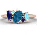 Atlantis London blue topaz and sapphire asymmetrical engagement ring in 18ct rose gold, front studio view showing the asymmetric gemstone setting and rose gold band, handmade in our London studio