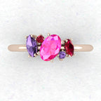 A top-down view of the Atlantis engagement ring featuring an asymmetrical cluster of pink and violet sapphires with a ruby in 18ct rose gold.