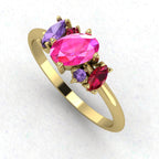 An angled perspective of the Atlantis engagement ring, showcasing the diverse colours of the sapphires and ruby against the polished yellow gold.