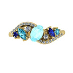 Top view of the Atlantis Storm 18ct yellow gold ring with a central aquamarine and blue sapphire cluster.