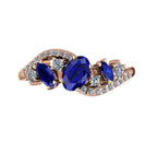 Top-down hero shot of the Atlantis Storm 18ct rose gold ring, featuring a cluster of deep blue sapphires and sparkling white diamonds.