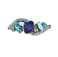 Top-down hero shot of the Atlantis Storm white gold ring with a violet-blue tanzanite, zircons, and aquamarines.