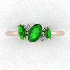 A top-down view of the Atlantis engagement ring, featuring an asymmetrical cluster of vivid green tsavorite garnets and sparkling diamonds in 18ct rose gold.