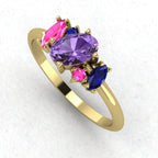 An angled perspective of the Atlantis ring, showcasing the organic design and the rich colour contrast of the sapphires and ruby against the yellow gold band.