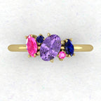 A top-down view of the Atlantis engagement ring featuring an asymmetrical cluster of violet and pink sapphires accented by a ruby in 18ct yellow gold.