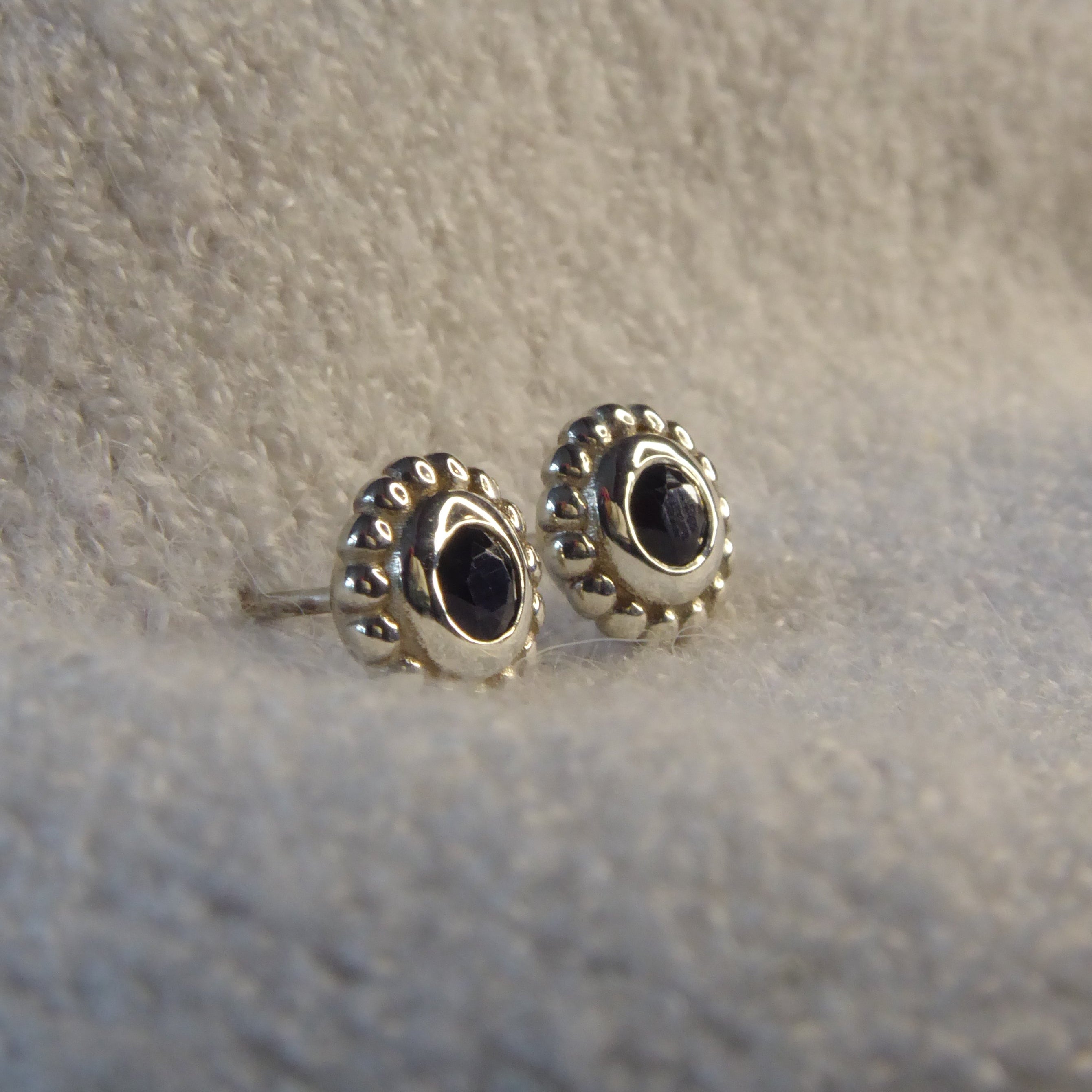 Side view of a silver black spinel stud earring showing the setting height and polished sterling silver post.