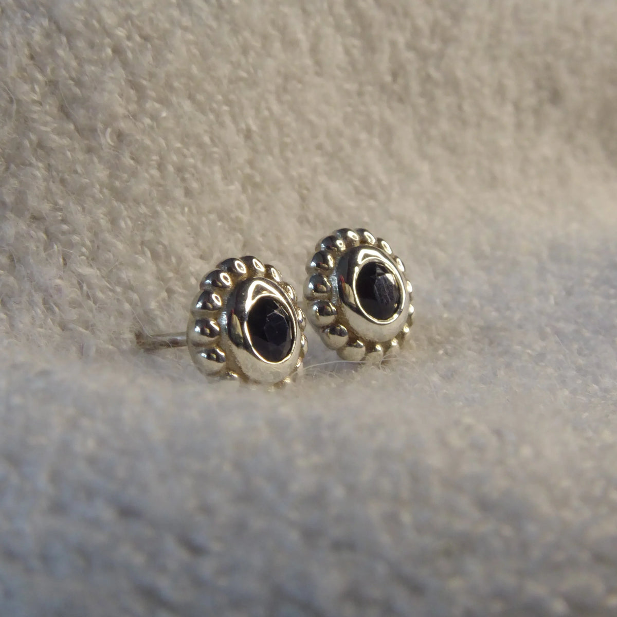 Side view of a silver black spinel stud earring showing the setting height and polished sterling silver post.