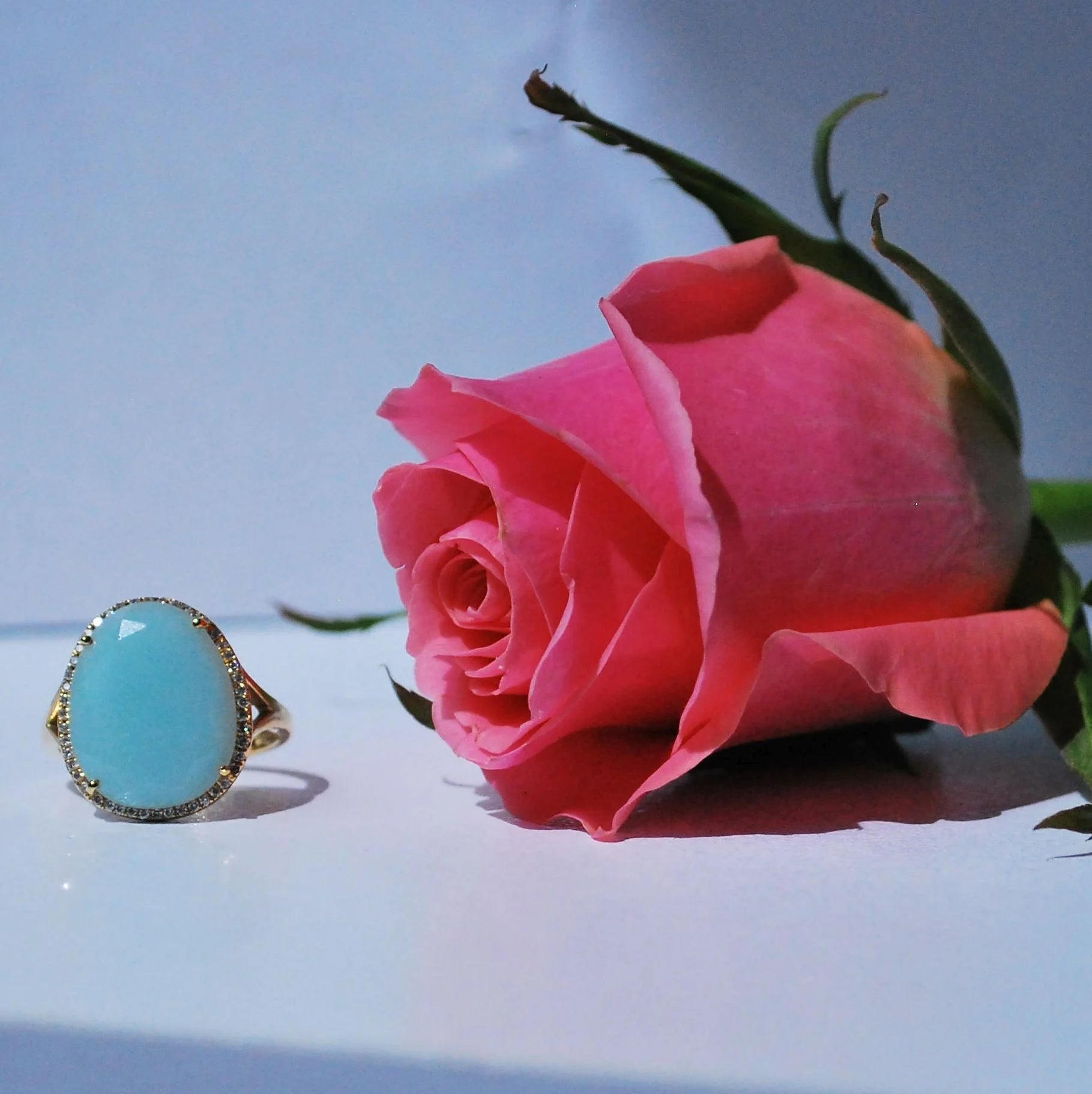 Large cabochon cut blue chalcedony ring set in 18ct yellow gold with a brilliant cut diamonds halo with rose.