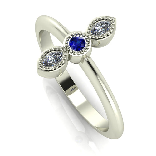 Angled perspective of an 18ct white gold trilogy ring with a sapphire and diamonds featuring fine milgrain textured edges.