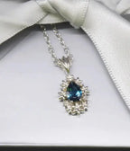 Fleur London Blue Topaz flower pendant in recycled sterling silver with adjustable chain on box
