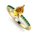 Side profile view of the yellow gold Calista ring, highlighting the detailed setting for the pear-cut sapphire and the emerald cluster shoulders.