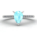Front three-quarter studio view of the Calista aquamarine ring, highlighting the brilliant white pavé diamonds set into the polished white metal shoulders.