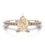 Top-down studio hero shot of the Calista ring, showcasing a prominent pear-shaped champagne diamond on a rose gold band with white diamond shoulders.