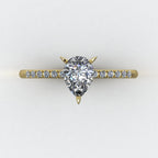 Calista engagement ring, top shaded view featuring a brilliant natural pear-shaped diamond on an 18ct yellow gold band with diamond shoulders.