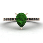 Top-down studio hero shot of the Calista engagement ring, featuring a vibrant pear-shaped green tourmaline on a rose gold band with black diamond shoulders.