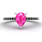 High angle studio detail shot of the Calista alternative engagement ring, showing the bright pink clarity of the sapphire facets against the dark shoulder stones.