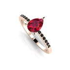 Front three-quarter studio view of the Calista ruby ring, showcasing the striking contrast of 14 black diamonds set into the rose gold shoulders.