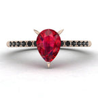 Front studio hero shot of the Calista engagement ring, featuring a 0.69ct pear-shaped red ruby on a thin recycled rose gold band with black diamonds.