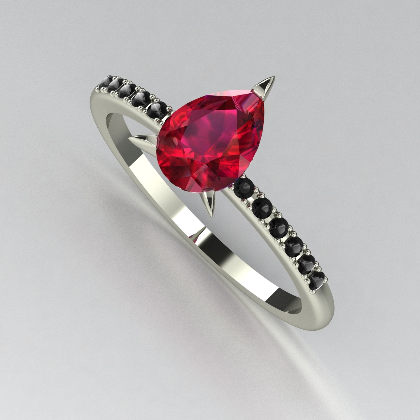 Top-down studio hero shot of the Calista engagement ring, featuring a vibrant pear-shaped red ruby on a precious metal band with black diamond shoulders.