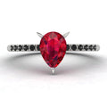 Front studio view of the Calista ruby ring, showcasing the striking contrast of the black diamonds set into the polished white metal shoulders.