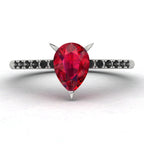 Front studio view of the Calista ruby ring, showcasing the striking contrast of the black diamonds set into the polished white metal shoulders.