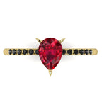 Top-down studio hero shot of the Calista engagement ring, featuring a vibrant pear-shaped red ruby on an 18ct yellow gold band with black diamond shoulders.